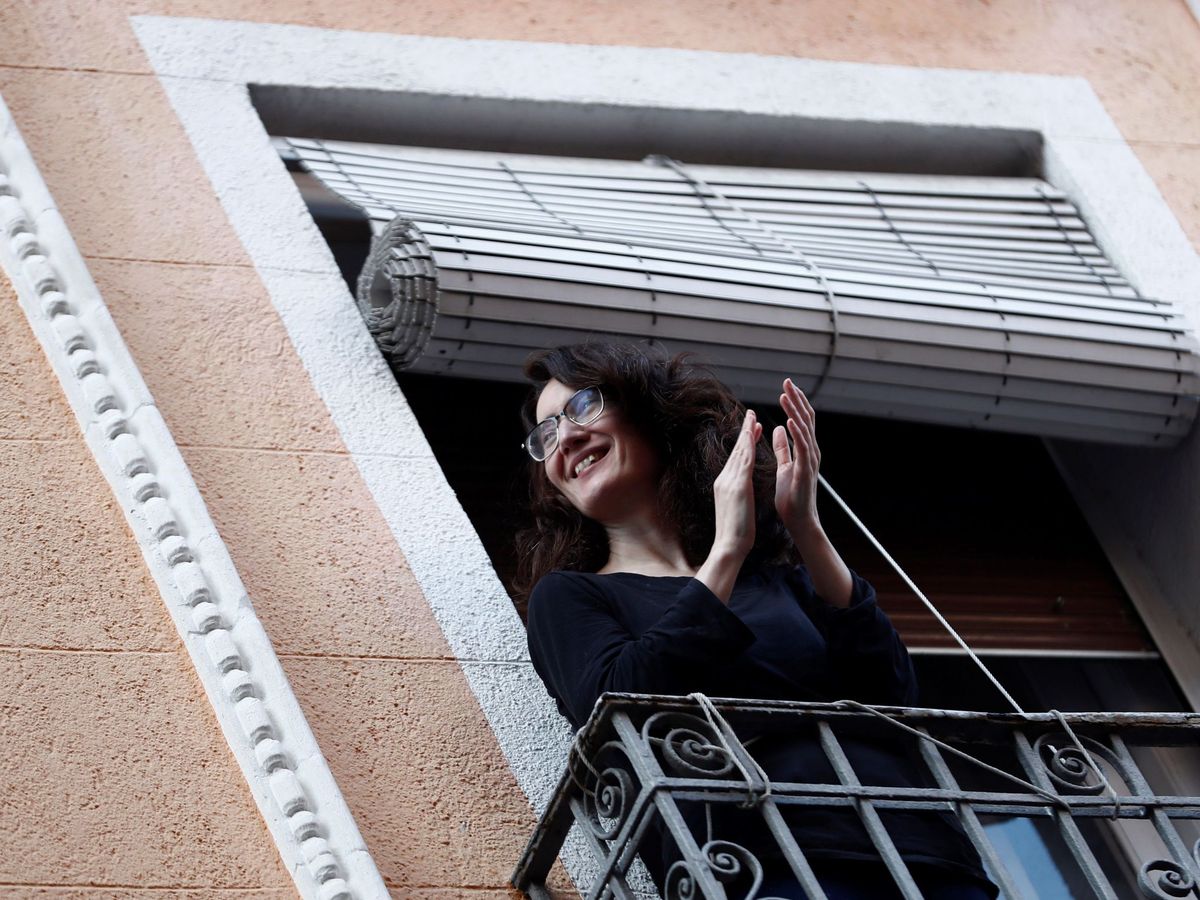 Foto: Una vecina del madrileño barrio de Lavapiés aplaude desde su balcón, este domingo. (EFE)
