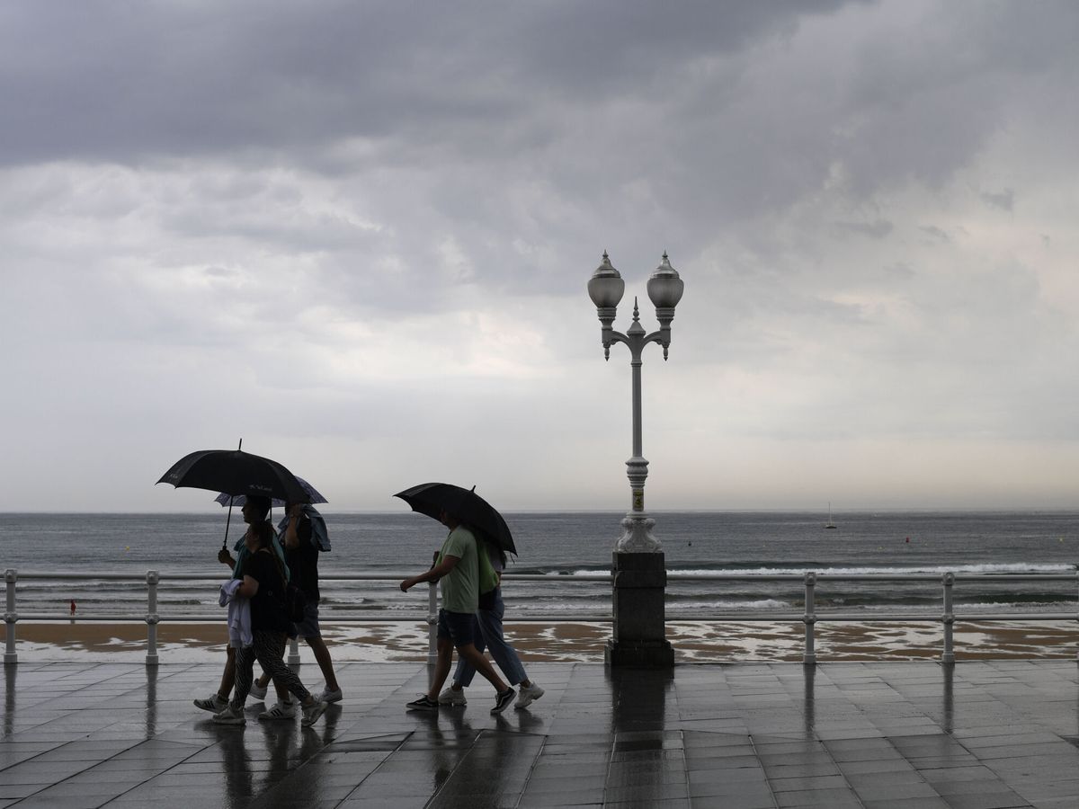 Foto: Varias personas se protegen con el paraguas de la lluvia. (EFE/Eloy Alonso)