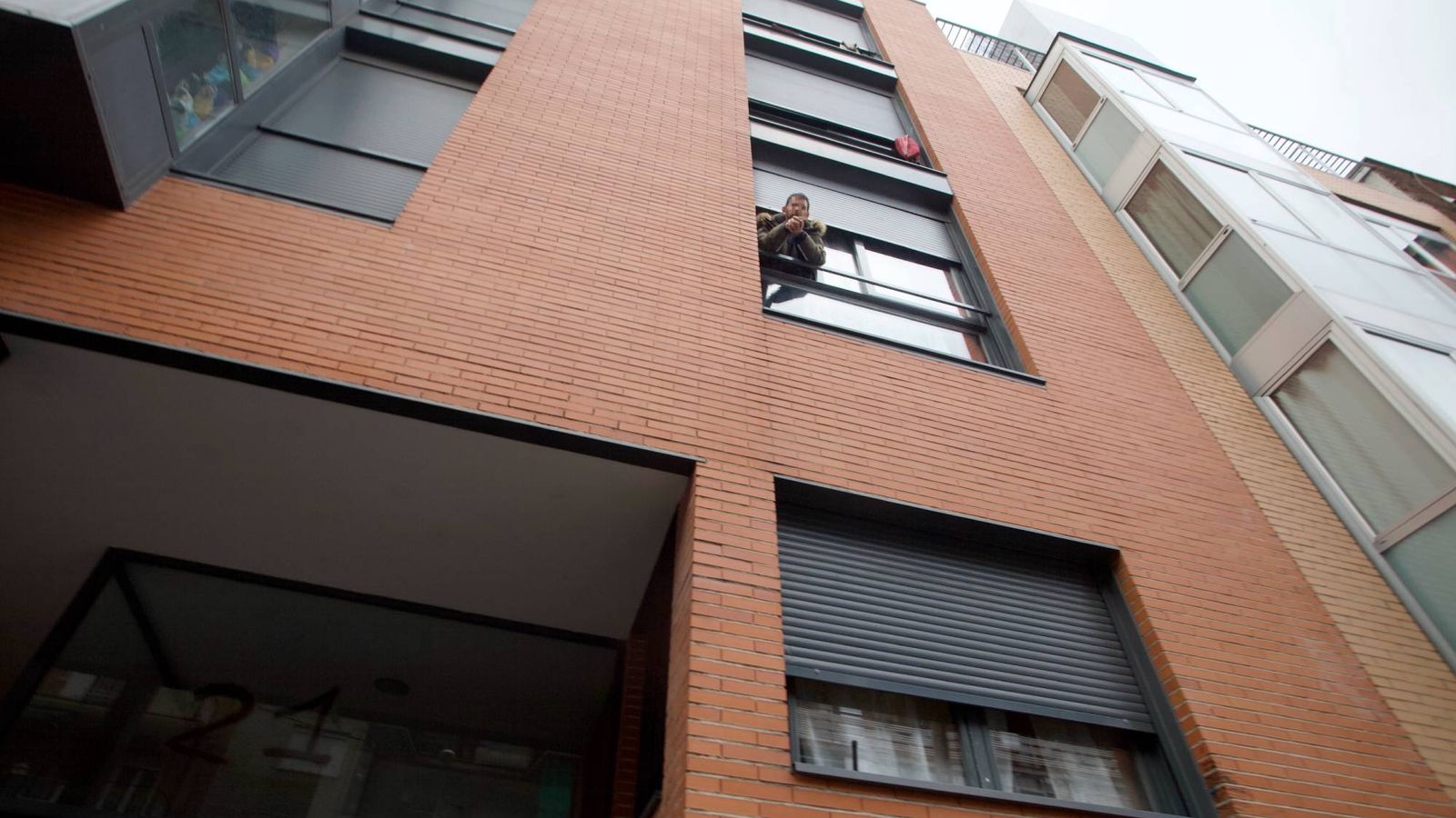 Foto: Un okupa se asoma a la ventana de un piso en Madrid. (Enrique Villarino)