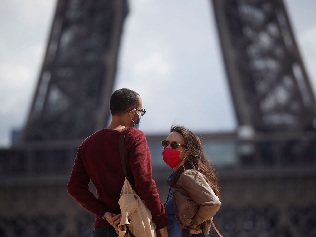 Foto: Una pareja con máscaras protectoras pasea cerca de la Torre Eiffel. (EFE)