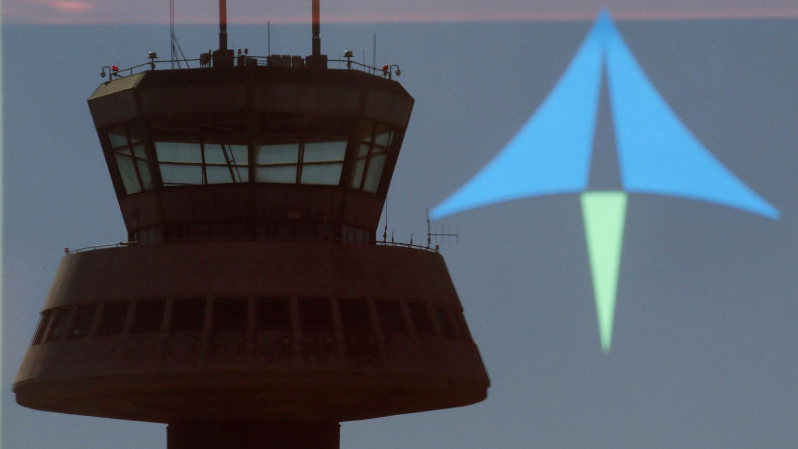 Foto: Una torre de control se refleja en una puerta de cristal con un logo de Aena en el aeropuerto de Barcelona. (Reuters)