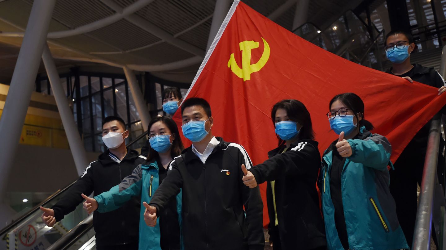 Trabajadores sanitarios chinos posan frente a la bandera del Partido Comunista Chino. (Reuters)