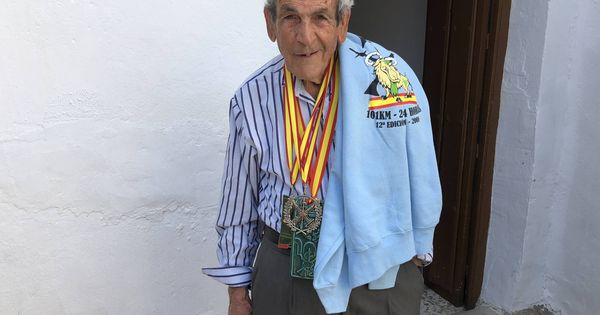 Foto: Súper Paco, en el patio de su casa de la barriada El Sexmo de Cártama, en Málaga, posando con una camiseta de los 101 kilómetros de Ronda y varias medallas de la competición. (Agustín Rivera)