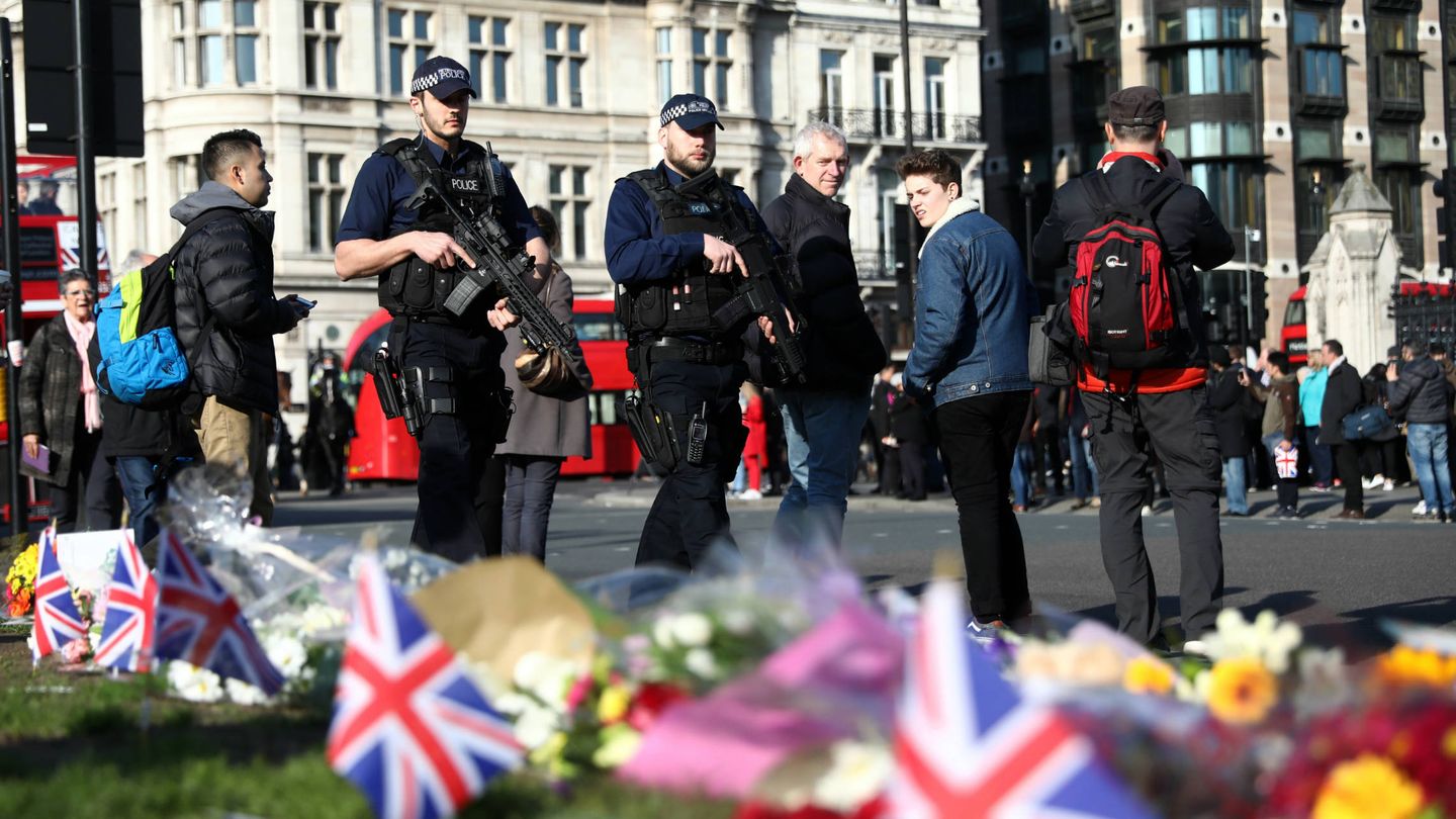 Agentes armados pasan ante unas flores en homenaje a las víctimas de los atentados, en Parliament Square. (Reuters)