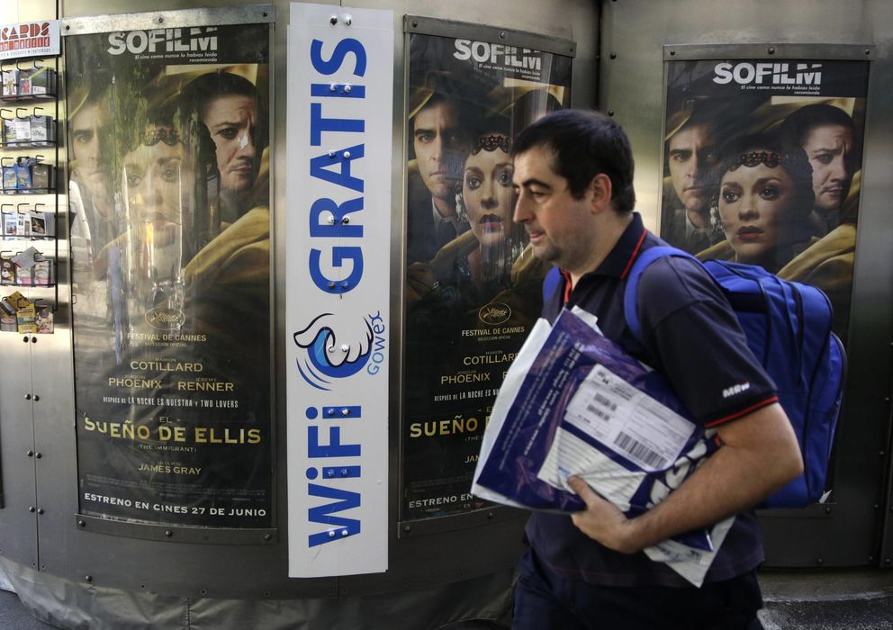 Foto: A man walks past a newspaper kiosk advertising spanish wireless network provider gowex in madrid