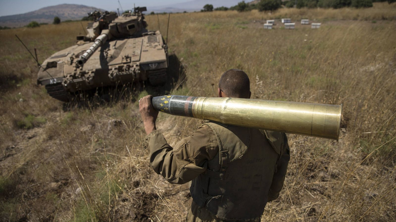 Foto: Un soldado israelí carga con un proyectil cerca de Alonei Habashan, en los Altos del Golán. (Reuters)