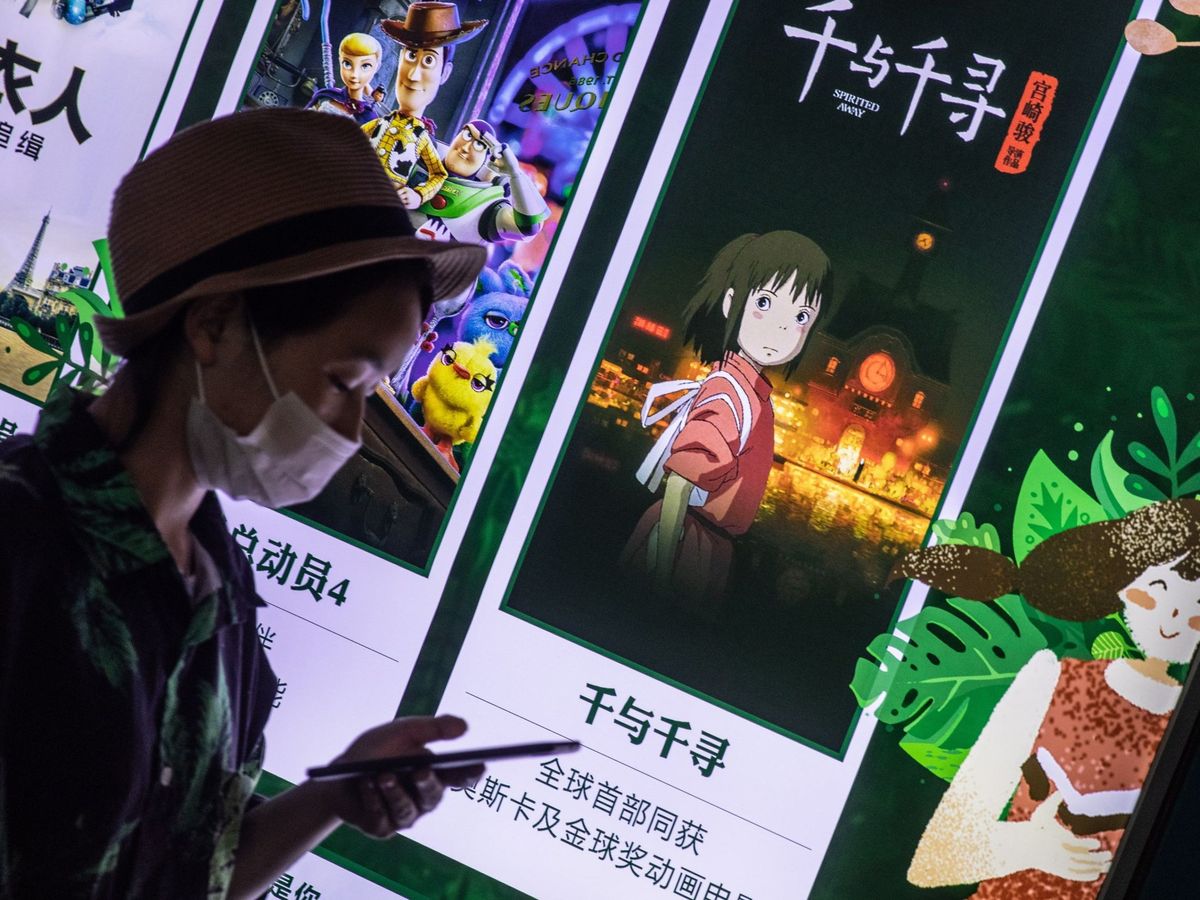 Foto: Una mujer pasea frente a un cartel de 'El viaje de Chihiro' en Pekín. (EFE)