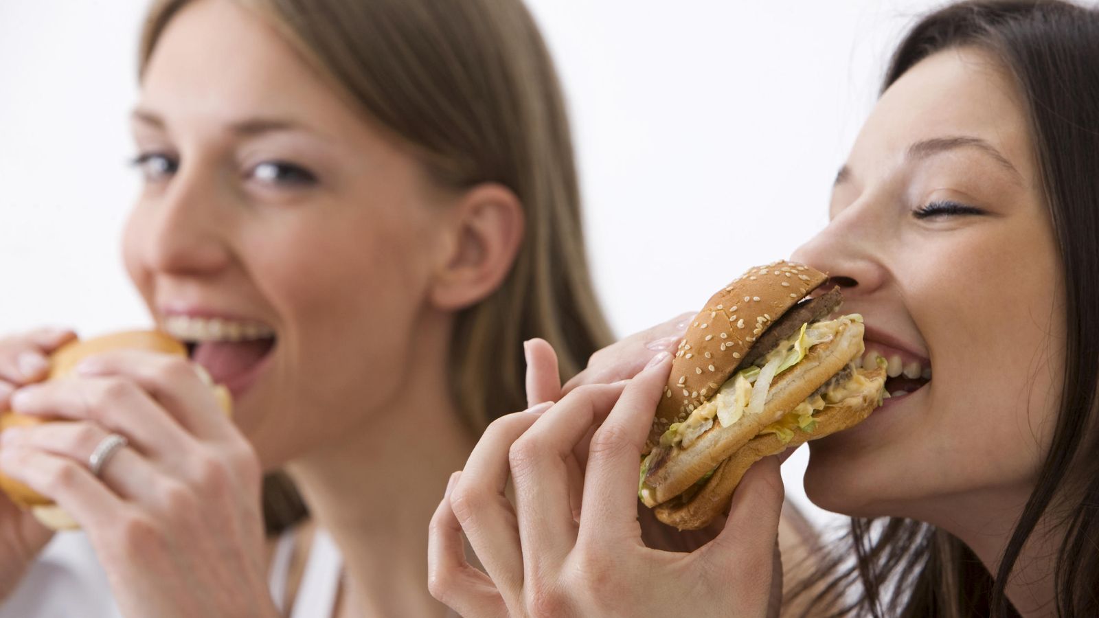 Foto: Dos chicas disfrutan de una hamburguesa. (iStock)