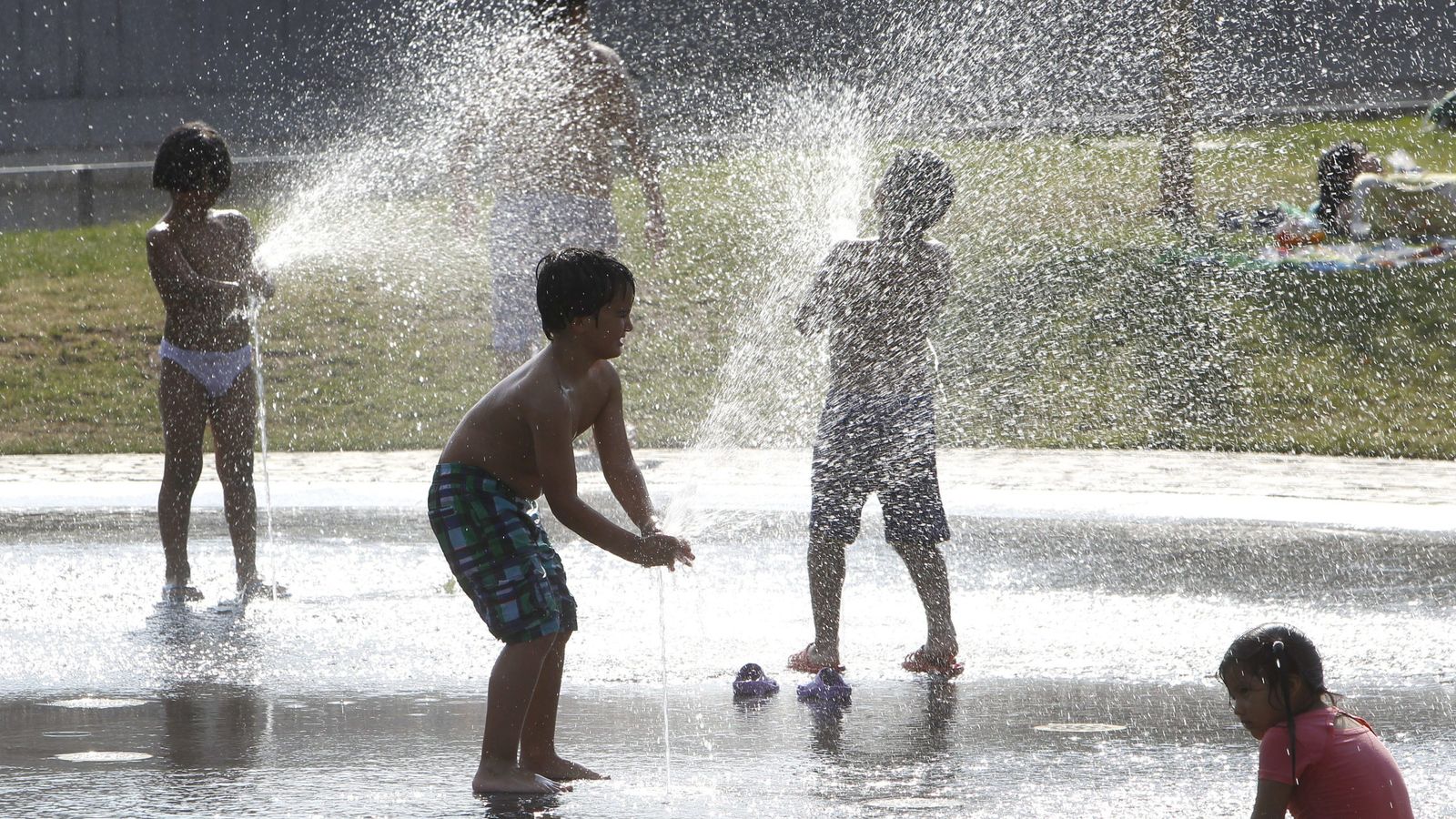 Foto: Varios niños se refrescan bajo el agua de una fuente esta tarde en el parque Madrid Río el pasado verano. (EFE)