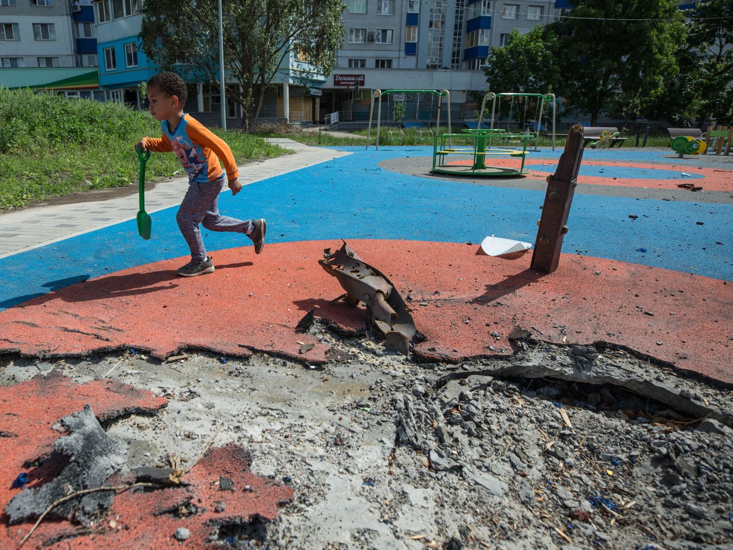 Un niño ucraniano de 4 años juega en un parque infantil parcialmente destruido por los bombardeos rusos en Járkov, Ucrania. (EFE/Esteban Biba)