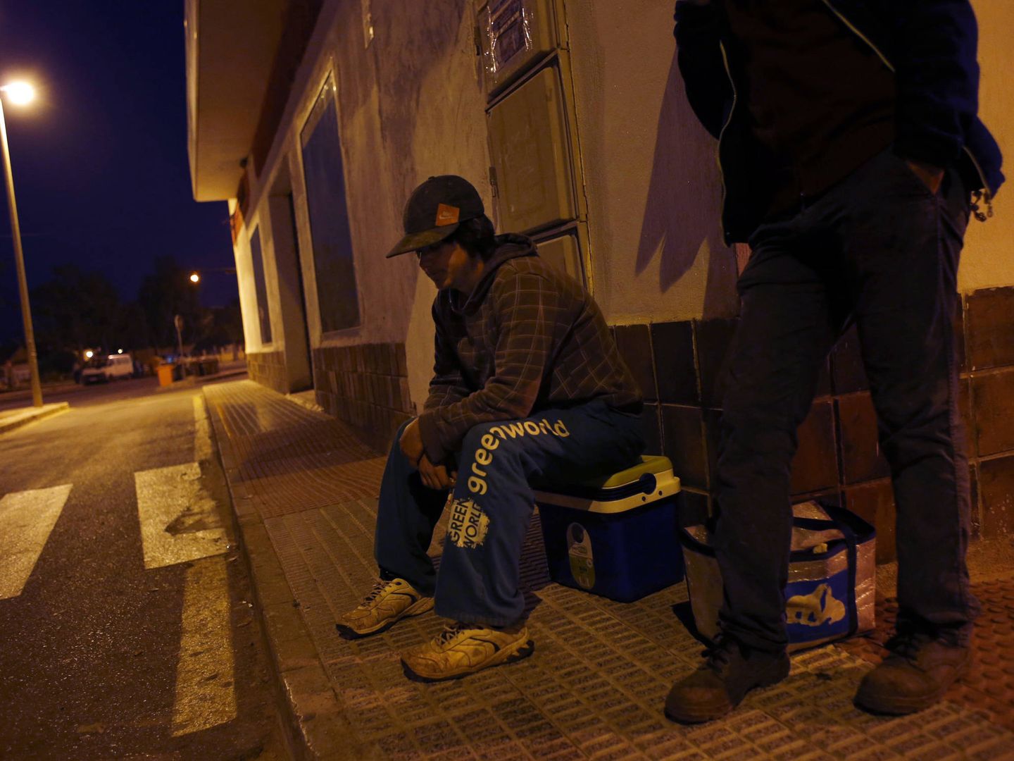 Un jornalero espera de madrugada a ser recogido para ir a los campos en Cartagena. (Reuters)