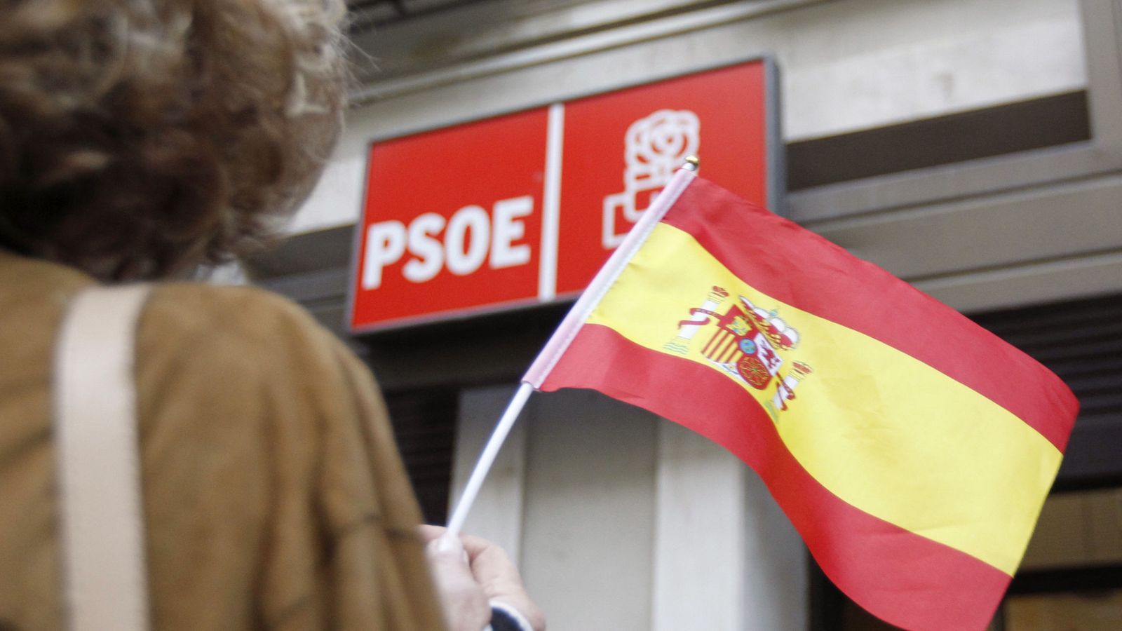 Foto: Una mujer ondea una bandera española frente a la sede socialista en la calle Ferraz de Madrid. (EFE)