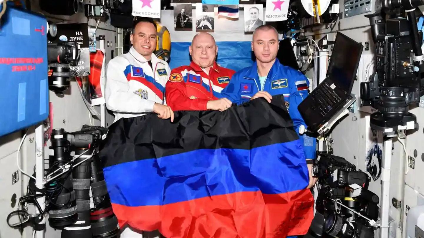 Los cosmonautas rusos Oleg Artemyev, Denis Matveev y Sergey Korsakov con la bandera de la república no reconocida de Donetsk, autoproclamada por los rusófilos en territorio ucraniano. (Roscosmos)