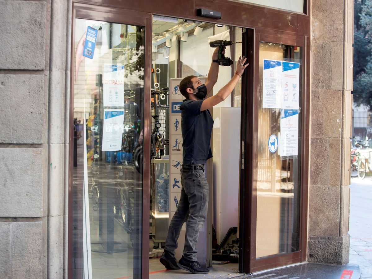 Foto: Operarios refuerzan los acceso a una tienda que sufrió pillajes durante los disturbios de Barcelona. (EFE)