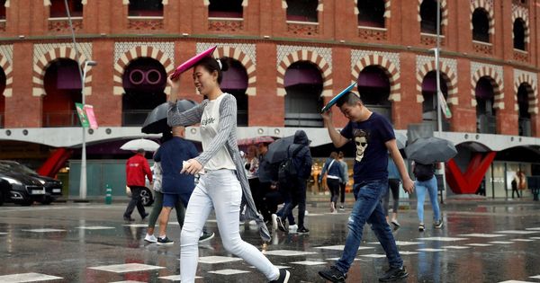 Foto: Varias personas caminan bajo la lluvia frente a la plaza de toros de Barcelona. (EFE)