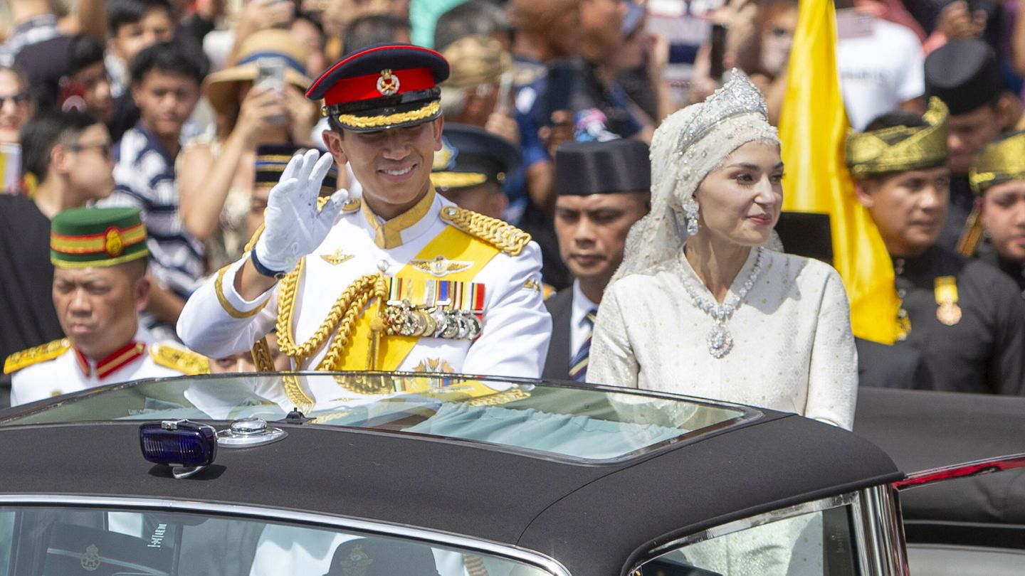 Abdul Mateen y Anisha Rosnah saludan a los ciudadanos reunidos en la capital de Brunéi para presenciar su boda. (EFE/Rudolf Portillo)