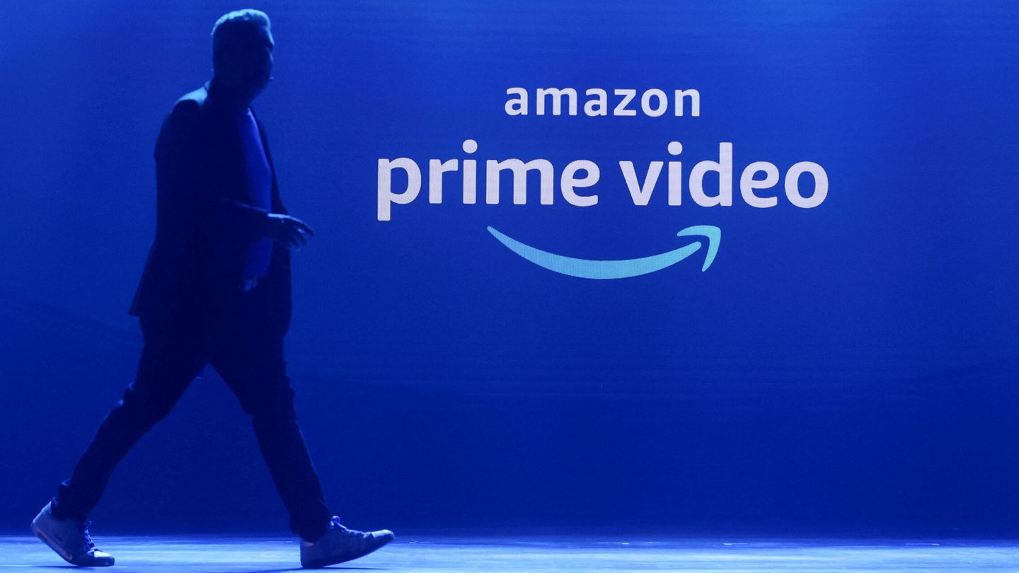 Un hombre camina junto a un cartel corporativo de Amazon Prime Video.
