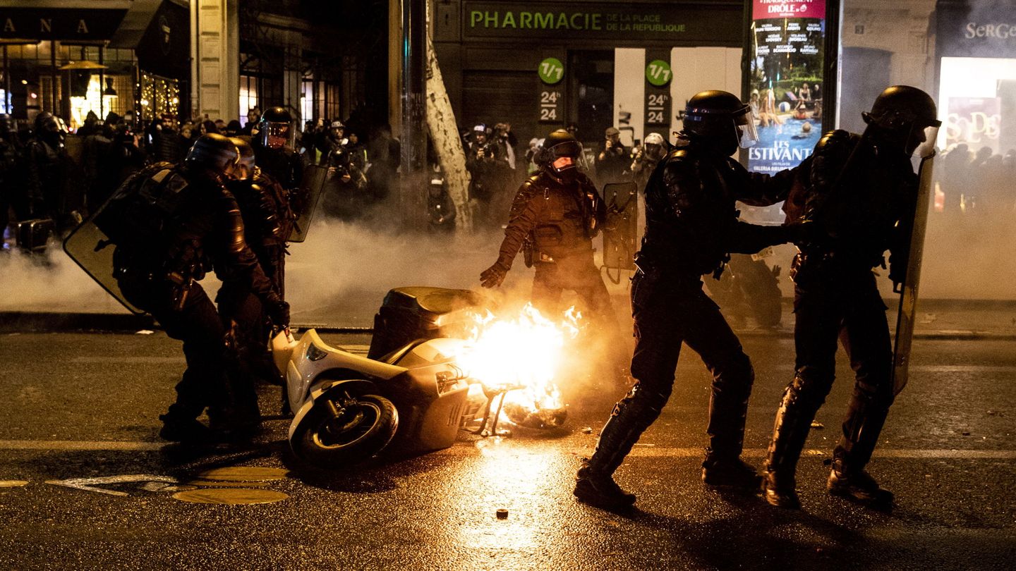 Agentes de policía retiran una moto en llamas durante los disturbios en los Campos Elíseos de París, el 26 de enero de 2019. (EFE)