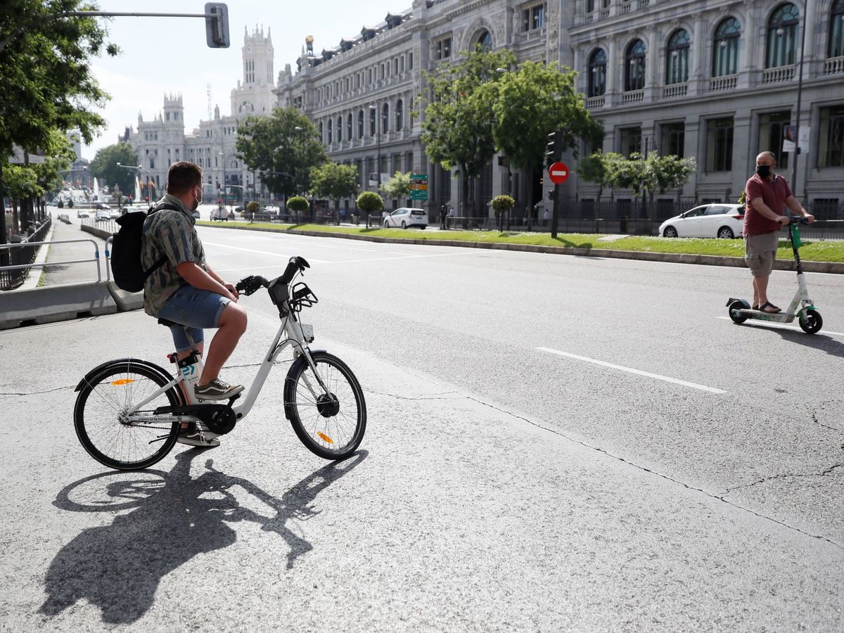 Foto: Una hombre transita la madrileña calle Alcalá con una bicicleta del servicio Bicimad. (EFE/Mariscal)