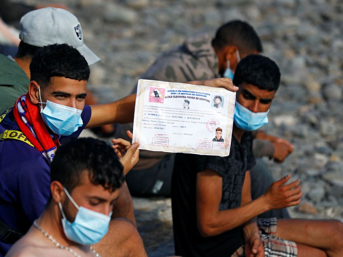 Foto: Un migrante muestra su certificado de estudios. (Reuters)