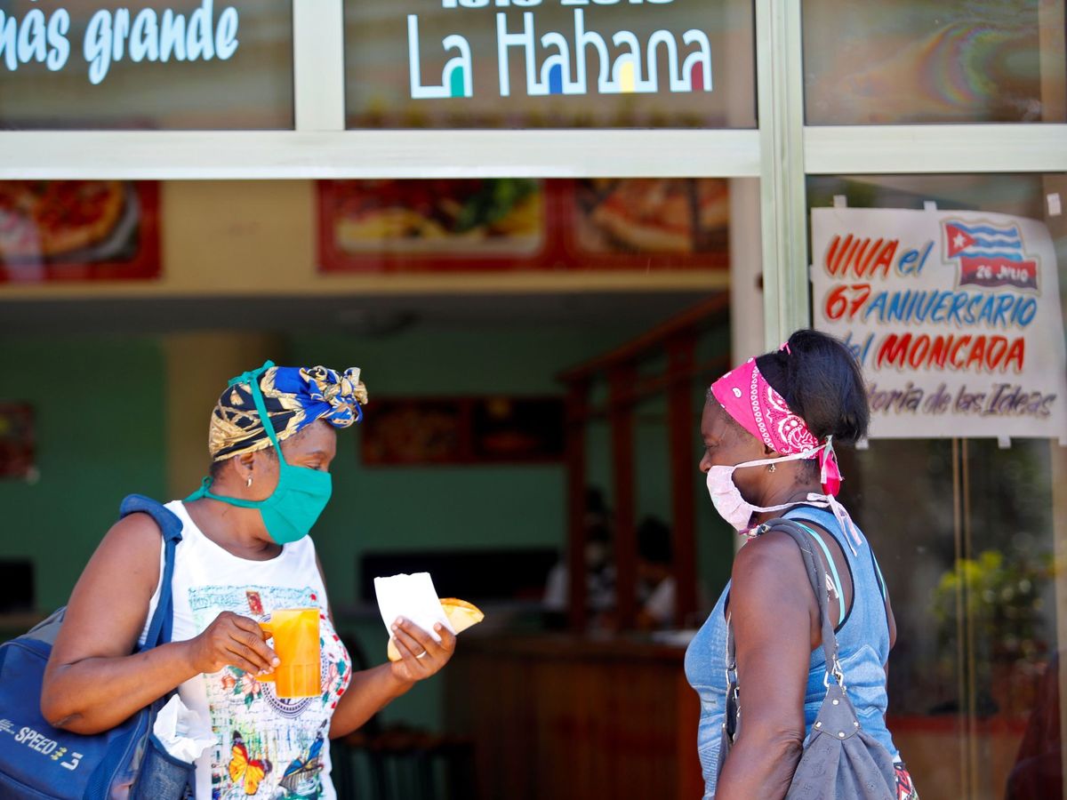 Foto: Dos mujeres protegidas con tapabocas conversan en la entrada de una cafetería este martes, en La Habana (EFE)