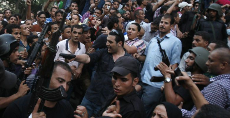 A plain clothes policeman points his gun as security forces escort Muslim Brotherhood members through supporters of the interim government installed by the army from the al-Fath mosque on Ramses Square in Cairo