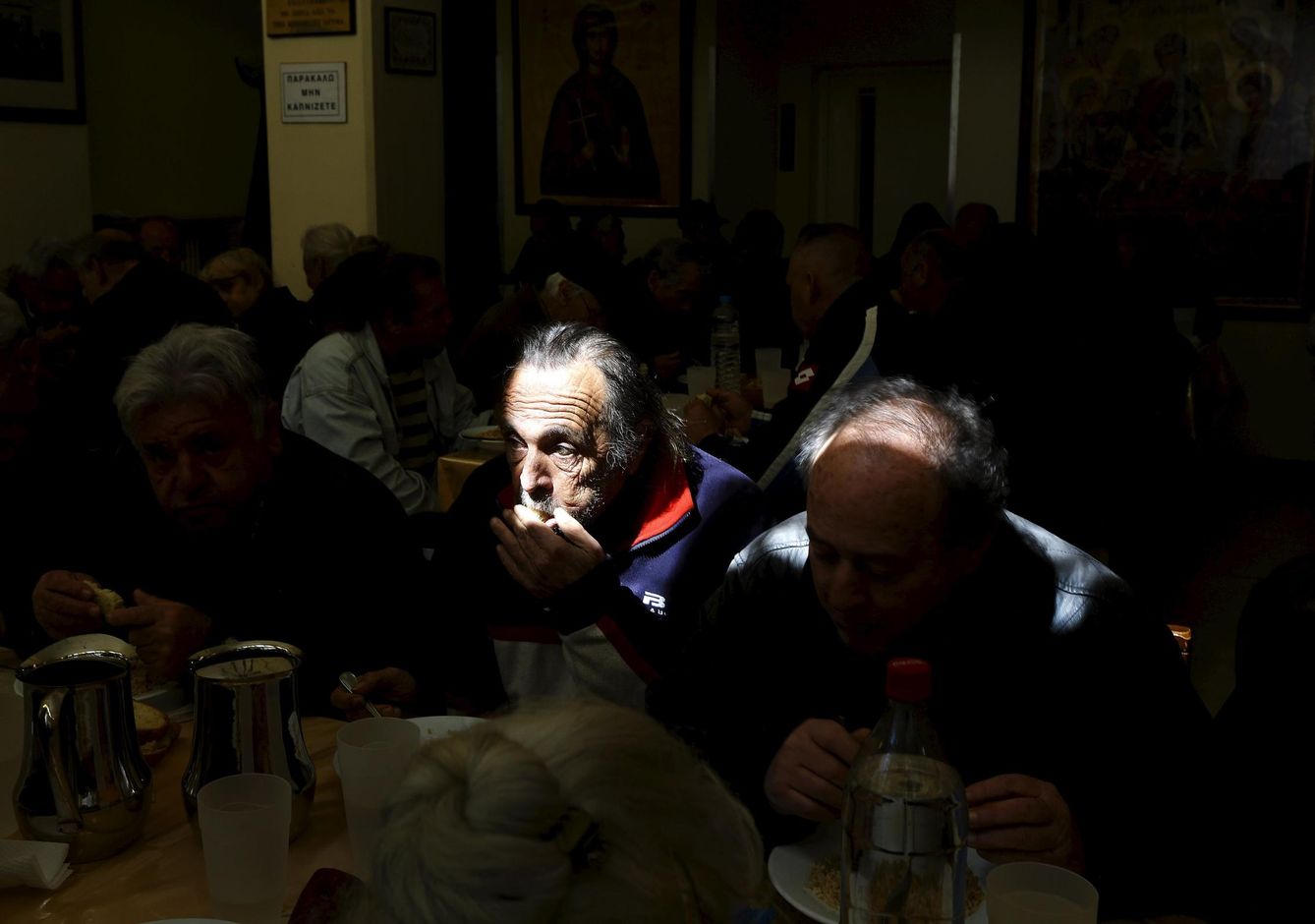 Griegos sin recursos comen en un centro de distribución de alimentos en Atenas (Reuters).