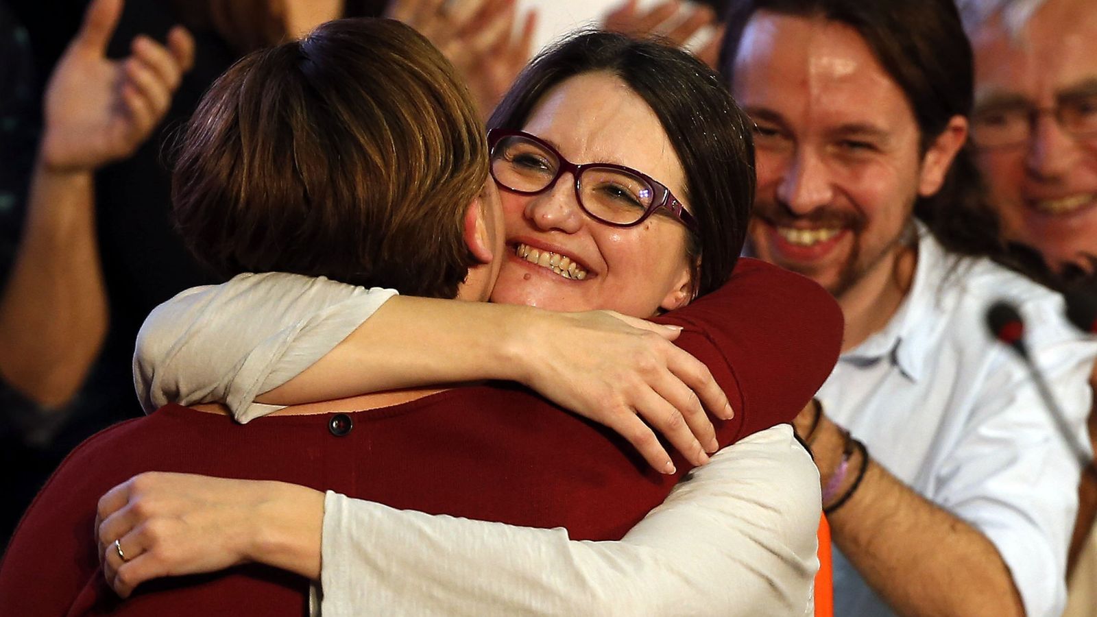 Foto: Colau y Oltra abrazándose en presencia de Iglesias. (EFE)