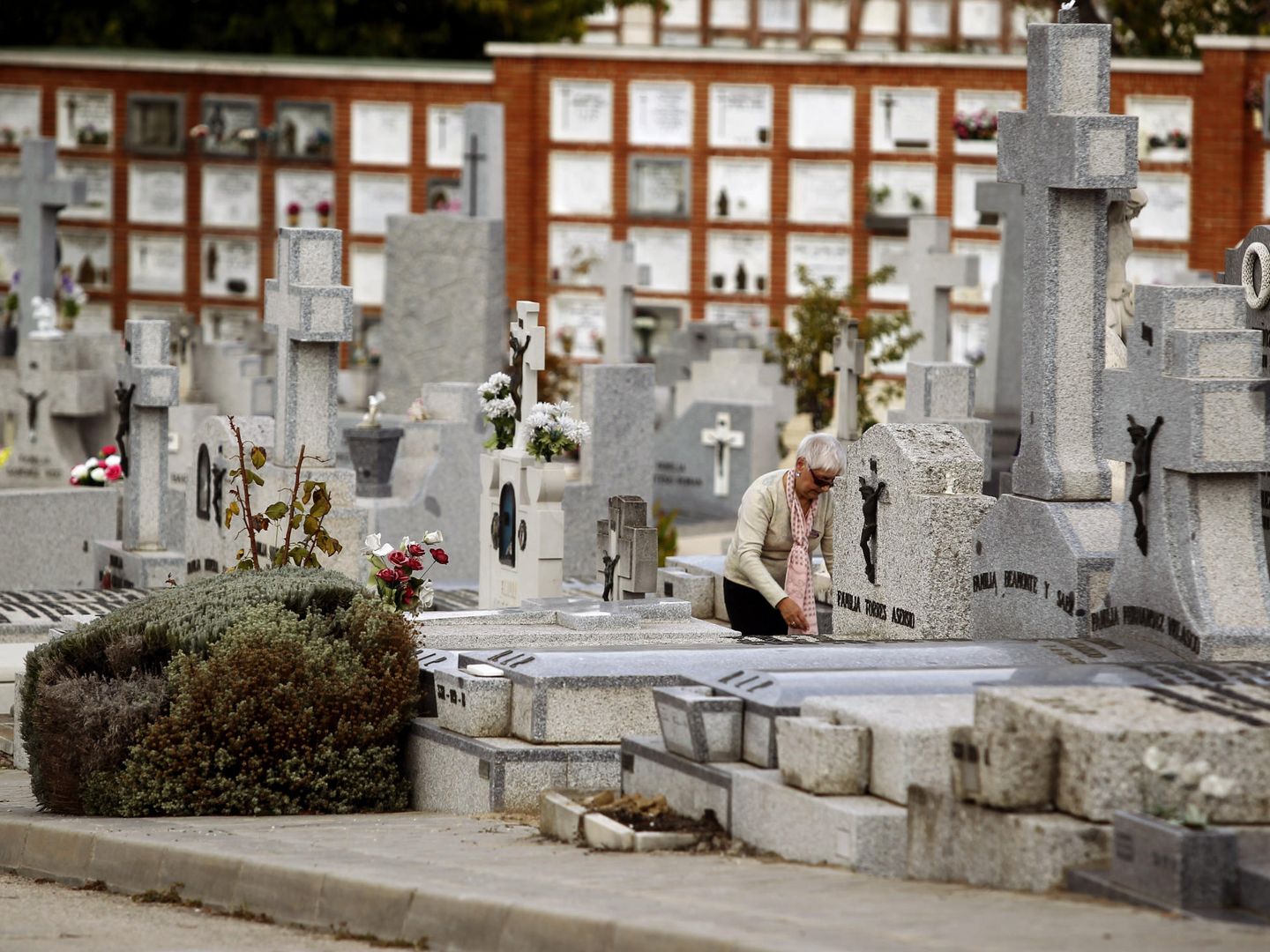 Una mujer limpia una tumba en el madrileño cementerio de La Almudena. (EFE)
