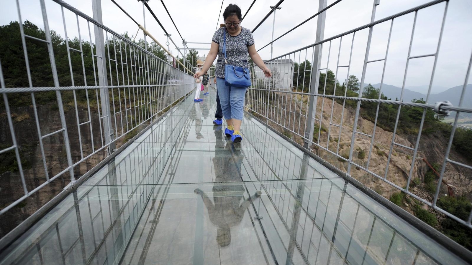 Foto: Turistas observan la altura mientras cruzan una pasarela de cristal en el Parque Nacional Shiniuzhai, en la provincia de Hunan, China (Reuters). 