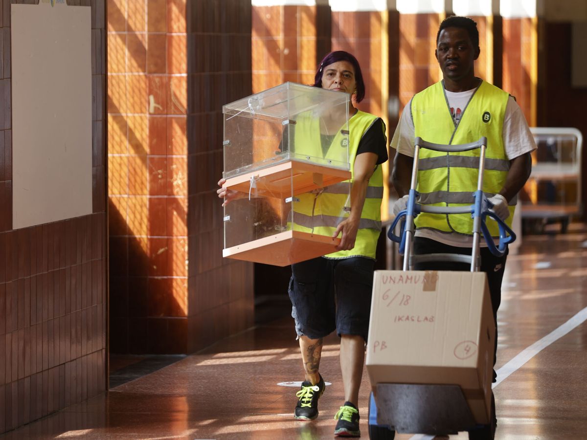 Foto: Dos personas portan una urna y papeletas en un colegio electoral en Bilbao. (EFE/Luis Tejido)