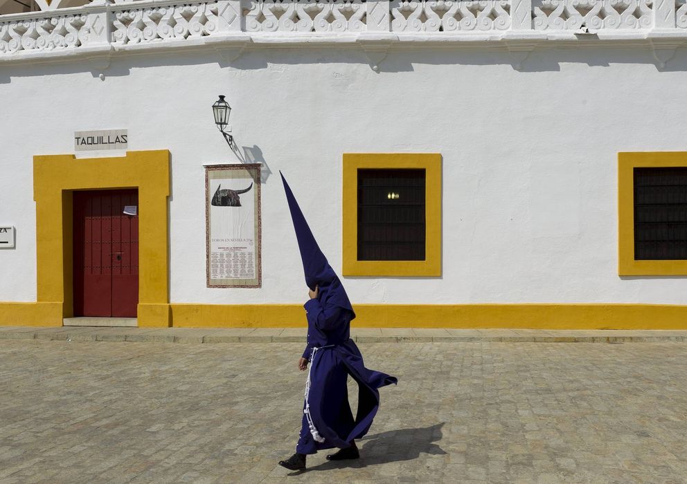 Foto: Un nazareno de la Hermandad del Baratillo pasa junto a la plaza de toros de la Real Maestranza. (EFE)