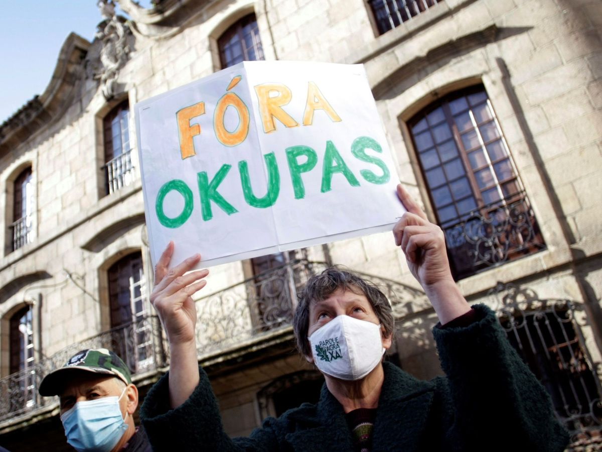 Foto: Una mujer sostiene una cartel con la frase "fuera okupas". (EFE/Cabalar)