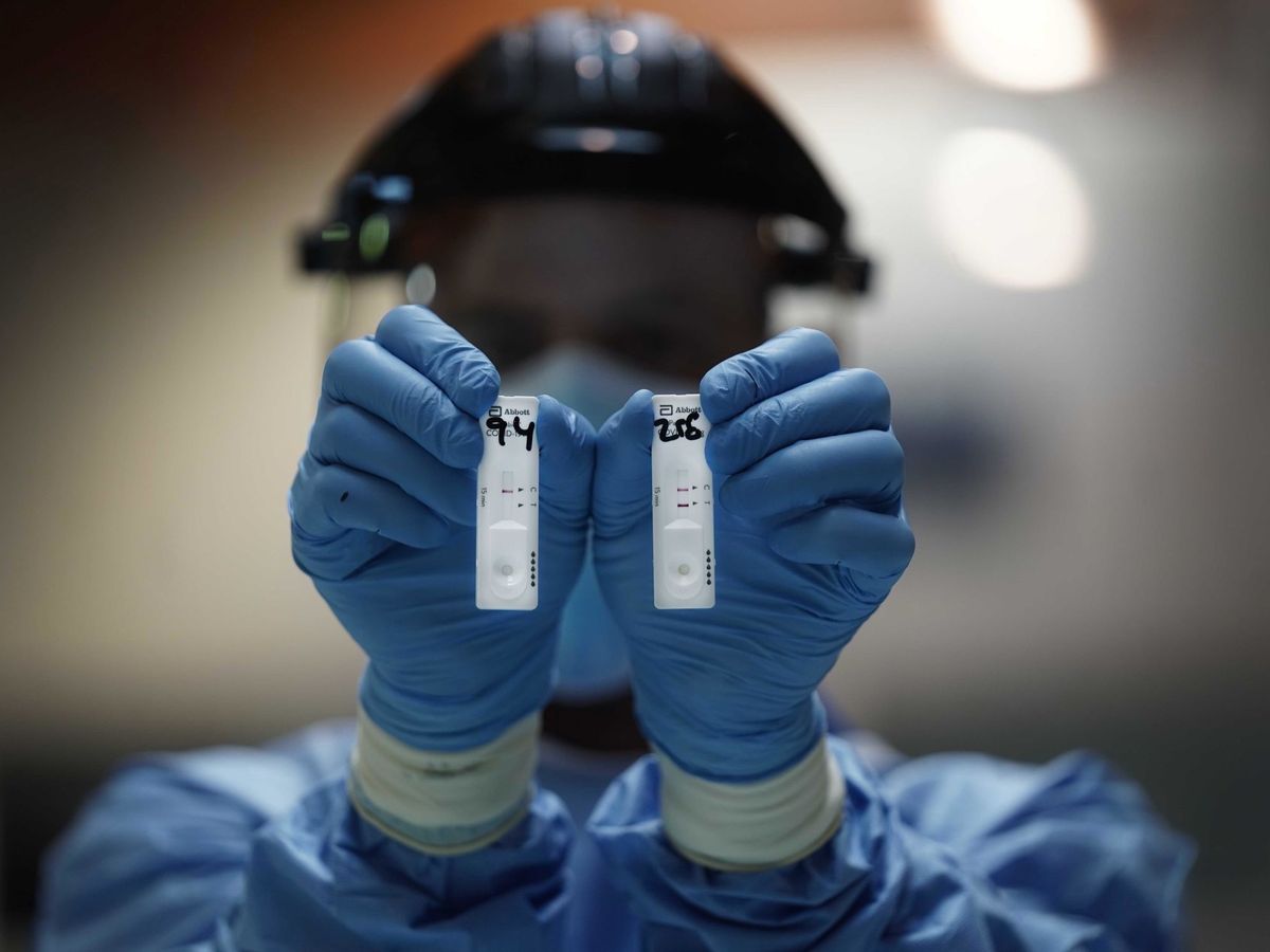 Foto: Un sanitario sostiene dos pruebas de test rápido de antígenos. (EFE) 