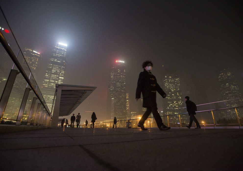 Foto: Un hombre con mascarilla camina por el distrito financiero de Shanghái bajo un manto de polución (Reuters).