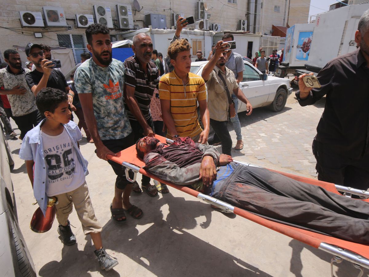 Foto: Un grupo de palestinos lleva a uno de los heridos tras los bombardeos en el campo de refugiados de Nuseirat. (Omar Naaman)