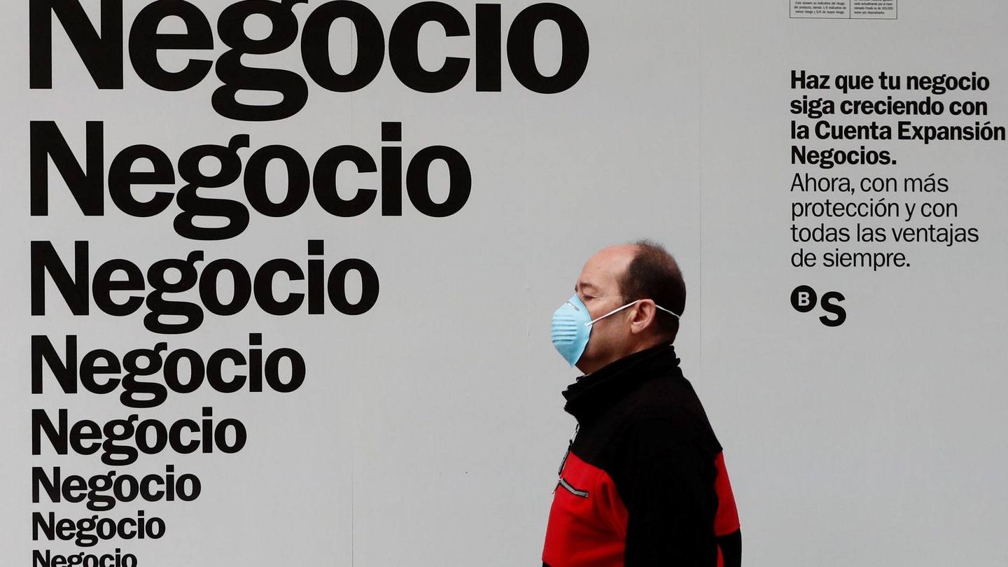 Un hombre protegido con mascarilla pasa delante de un cartel publicitario este martes. (EFE)