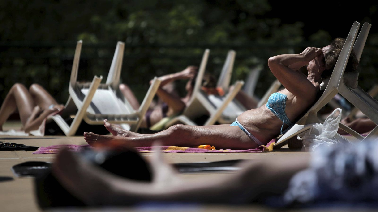 Foto: Varios bañistas toman el sol en la piscina municipal al aire libre del Canal de Isabel II. (EFE)
