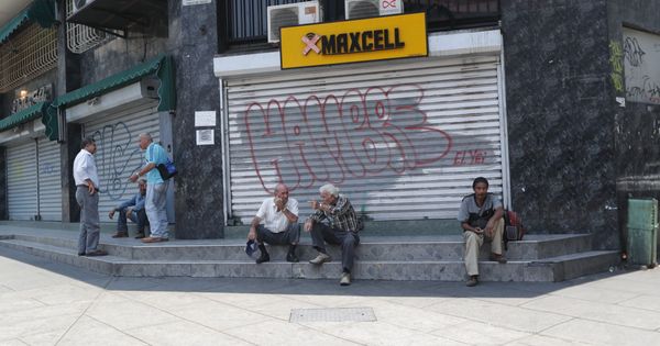 Foto: Varias personas conversan a las afueras de locales comerciales cerrados debido a un apagón en Caracas (Venezuela). (EFE)