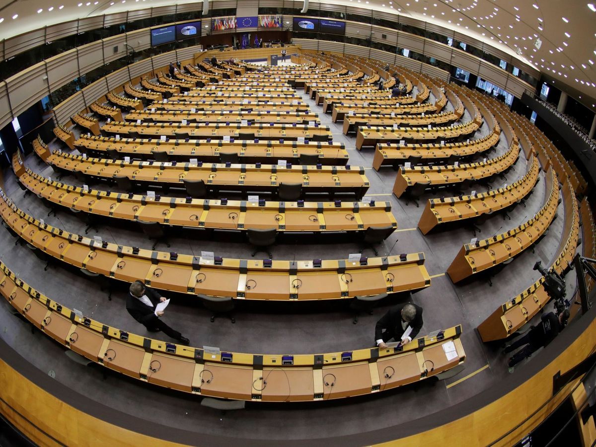 Foto: Varios empleados del Parlamento Europeo apuntalan los últimos detalles del hemiciclo antes de una sesión plenaria. (EFE/Olivier Hoslet)