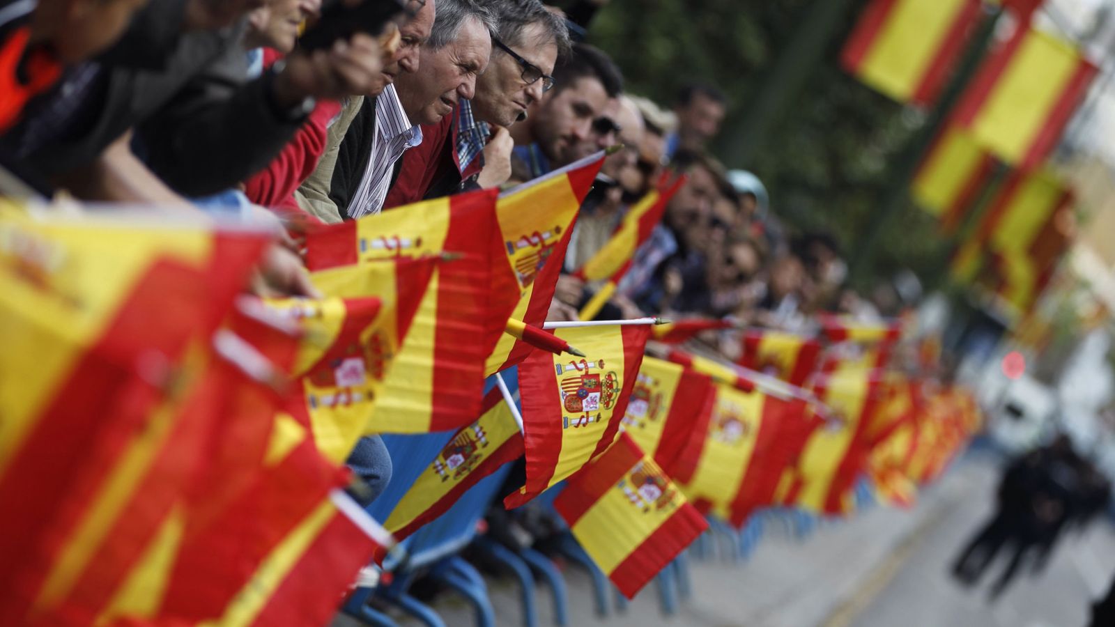 Foto: Asistentes al acto central del Día de las Fuerzas Armadas portan banderas de España. (EFE)