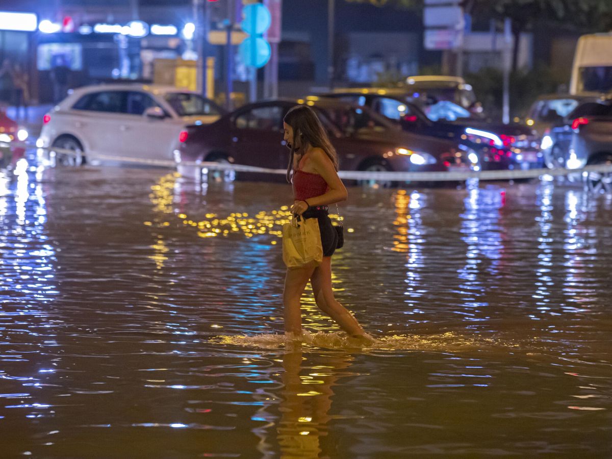 Foto: Una joven cruza la avenida Juan de Borbón de Murcia, inundada tras la tormenta de este viernes. (EFE/Marcial Guillén)
