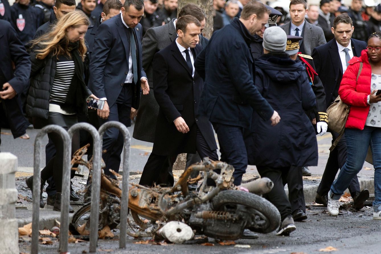 El presidente francés, Emmanuel macron, pasa junto a una motocicleta calcinada mientras comprueba personalmente los daños materiales ocasionados en las protestas, el 2 de diciembre de 2018. (EFE)