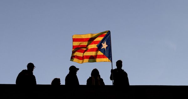 Foto: Varios vecinos ondean una bandera independentista en Barcelona. (EFE)