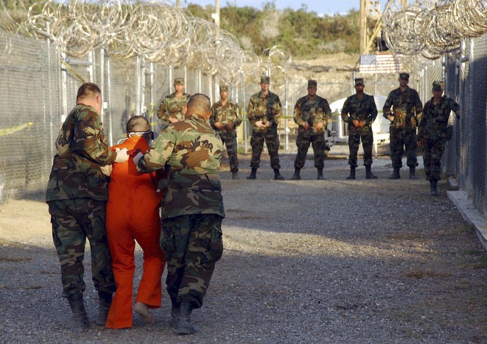 Foto: Dos militares estadounidenses conducen a un presunto yihadista al interior de la base de Guantánamo (Reuters).