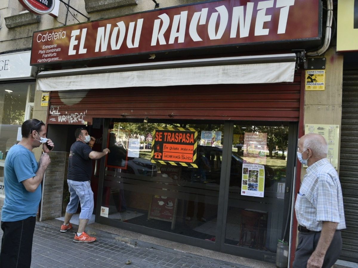 Foto: Un hombre en Lleida cierra su bar, que luce un cartel de traspaso. (EFE)