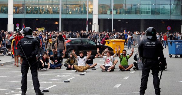Foto: Miembros de los Mossos d'Esquadra controlan a las centenares de personas que se agolpan ante el Aeropuerto del Prat. (EFE)