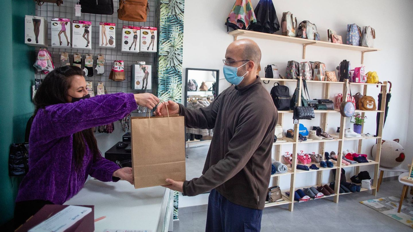 Cristina Carnero, propietaria de Mis Zapatos y Complementos, entregando un paquete al repartidor de Mojizon. (Fernando Ruso)