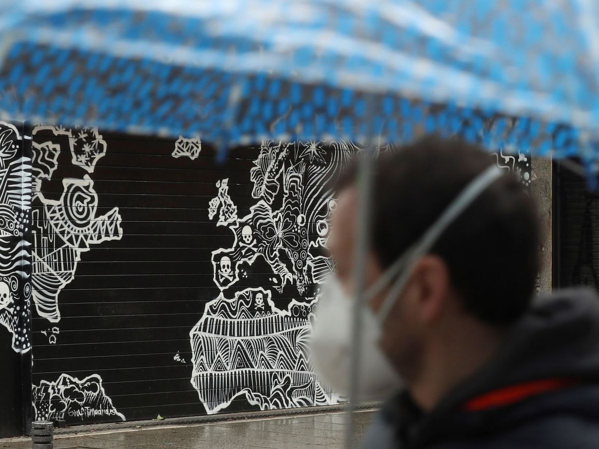Foto: Un hombre con mascarilla pasa ante un local cerrado, en Madrid. (EFE)
