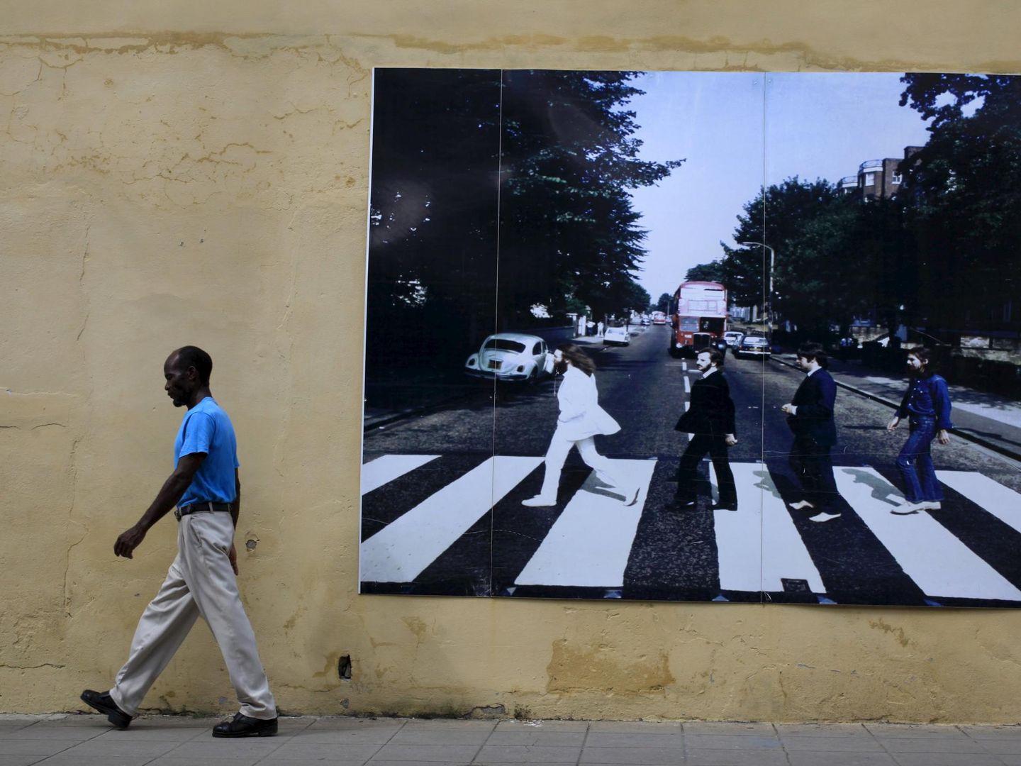 Un caminante pasa frente a una fotografía gigante de los Beatles en Camagüey, Cuba. (Reuters)